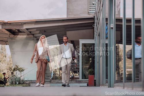 Image of Modern business couple after a long day's work, walking together towards the comfort of their home, embodying the perfect blend of professional success and personal contentment.