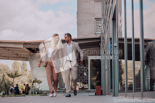 Image of Modern business couple after a long day's work, walking together towards the comfort of their home, embodying the perfect blend of professional success and personal contentment.