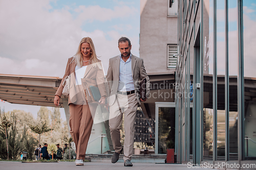 Image of Modern business couple after a long day's work, walking together towards the comfort of their home, embodying the perfect blend of professional success and personal contentment.