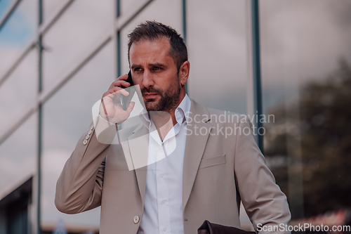 Image of A businessman using his smartphone outdoors, showcasing the seamless integration of technology and mobility in modern professional life.