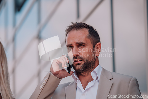 Image of A businessman using his smartphone outdoors, showcasing the seamless integration of technology and mobility in modern professional life.