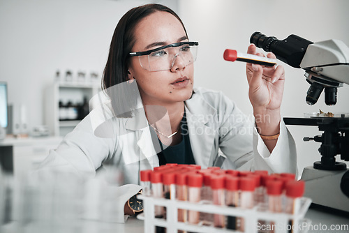 Image of Scientist, woman and blood test, microscope or laboratory research for DNA, virus analysis or medical study. Professional science or asian person in biotechnology, glasses or check red liquid in tube