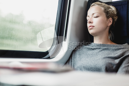 Image of Lady traveling napping on a train.