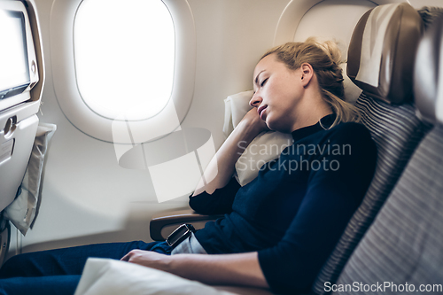 Image of Tired blonde casual caucasian woman napping on airplane.