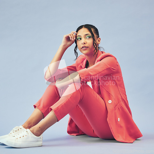 Image of Fashion, woman and sitting on floor in studio with thinking face and makeup for beauty, aesthetic and cosmetics with mockup. Serious, person and creative clothes on purple background for wellness