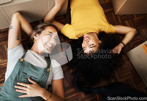 Image of Top view, lesbian and couple with boxes, homeowners and achievement with love, bonding and property. Queer people, lgbtq or happy women on the ground, new apartment and conversation with real estate
