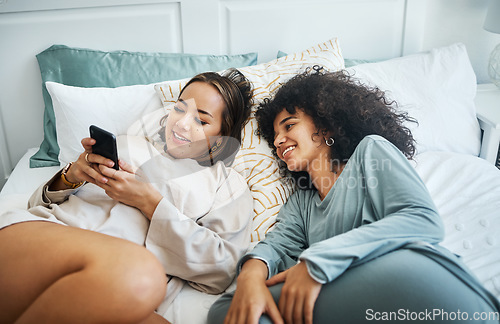 Image of Phone, social media and a lesbian couple in bed together in the morning for communication or to relax. Love, lgbt and a woman watching a movie or video with her girlfriend in the home bedroom