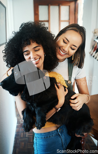 Image of Happy, smile and lesbian couple holding dog in modern apartment for bonding together. Love, family and interracial young lgbtq women hugging and embracing their sweet animal pet puppy at home.