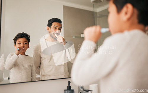 Image of Dad, boy and child brushing teeth in mirror for hygiene, morning routine and teaching healthy oral habits at home. Father, kid and dental cleaning in bathroom with toothbrush, fresh breath and care