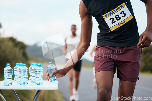 Image of Hand, water and a marathon runner in a race or competition closeup for fitness or cardio on a street. Sports, exercise or running with an athlete grabbing a drink while outdoor on a road for training