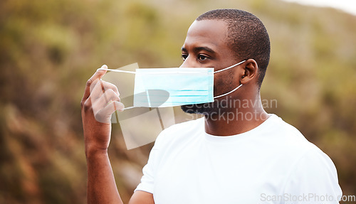 Image of Covid, outdoor and black man remove mask, safety and pandemic policy with freedom, breathing and decrease infection rates. African person, outside or guy take off face cover, regulations or protected