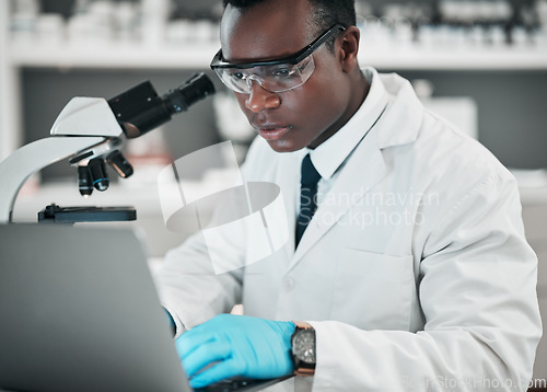 Image of Science, laptop and black man with research, medical and microscope with healthcare, typing and chemistry. African person, biologist or scientist with a computer, laboratory equipment and digital app