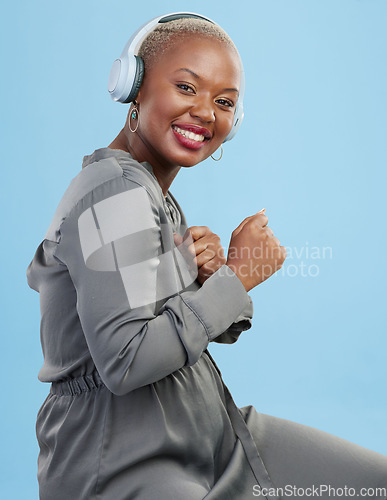 Image of Portrait, dance and happy black woman with music headphones in studio for audio streaming on blue background. Radio, face and African female model smile for podcast earphones, track or playlist