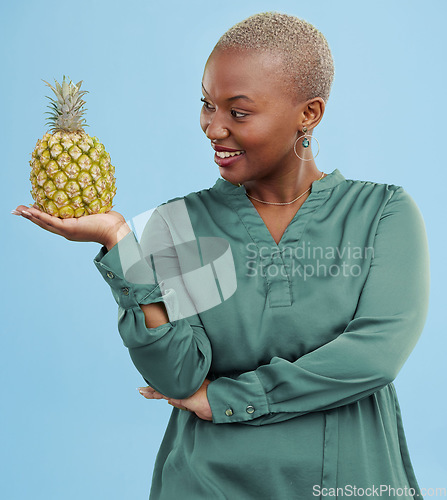 Image of Smile, pineapple for health or nutrition and a black woman in studio on a blue background for diet. Wellness, fruit or food with a happy young person looking confident for healthy eating or detox