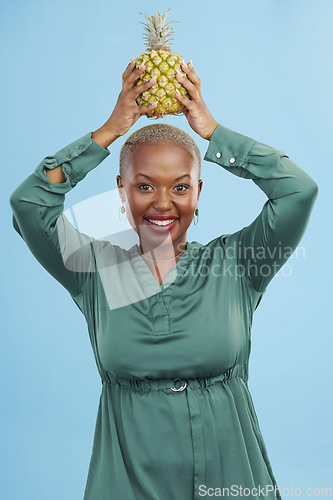 Image of Portrait, happy and black woman pineapple in studio for detox, lose weight or diet nutrition on blue background. Fruit, face and African lady nutritionist show vegan, lifestyle or organic diet choice