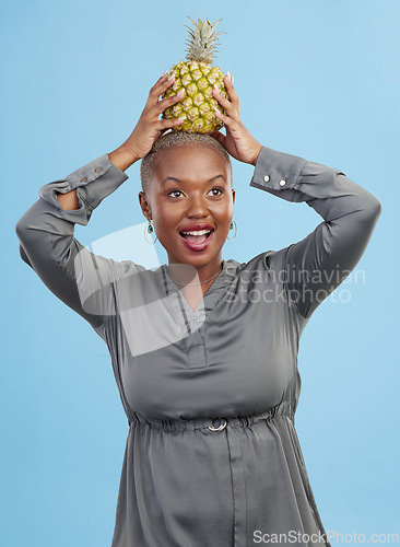 Image of Face, balance and black woman with pineapple in studio for detox, lose weight or diet nutrition on blue background. Fruit, care and African lady nutritionist show vegan, organic and diet snack choice