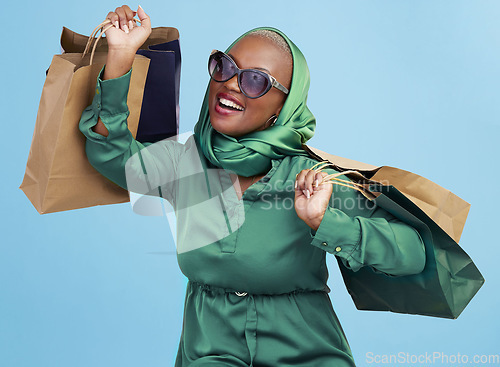 Image of Shopping bag, studio smile and black woman excited for luxury fashion spree, mall store sales or commerce deal. Retail therapy package, market gift choice and rich African customer on blue background