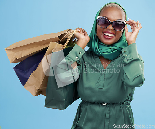 Image of Studio bag, shopping and black woman excited for holiday fashion spree, commerce discount or boutique giveaway deal. Financial freedom, luxury product and wealthy African customer on blue background