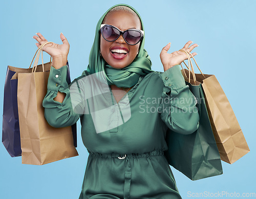 Image of Shopping bag, studio and black woman excited for fashion spree, mall store sales or boutique deal, giveaway or shop offer. Retail therapy gift, choice and wealthy African customer on blue background