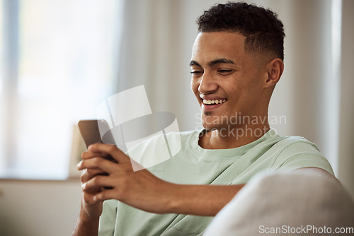 Image of Home, smile and man with a cellphone, relax and typing with connection, digital app or social media. Person on a couch, lounge or guy with a smartphone, meme and website info with internet or network