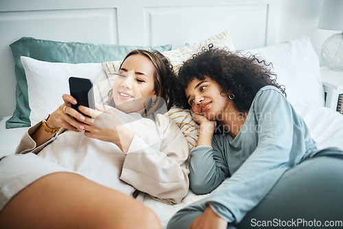 Image of Phone, love and a lesbian couple in bed together in the morning for communication or to relax. Social media, lgbt and a woman watching a movie or video with her girlfriend in the home bedroom