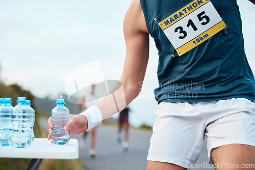 Image of Hand, water and running a marathon race for competition closeup with fitness or cardio on a street. Sports, exercise or health and a runner or athlete person with a drink while on a road for training