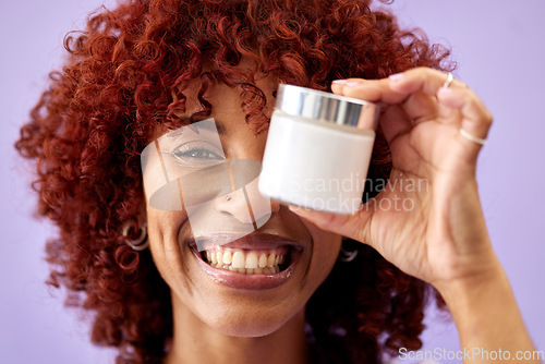 Image of Portrait, smile and product for skincare with a woman holding a container in studio on a purple background. Beauty, happy and promotion of a cream or serum for antiaging with a happy young model