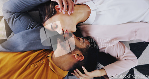 Image of Embrace, above and couple kiss on the floor for love, care and comfort in relationship. Happy, affection and a man and woman kissing for happiness, marriage and romance together with a smile