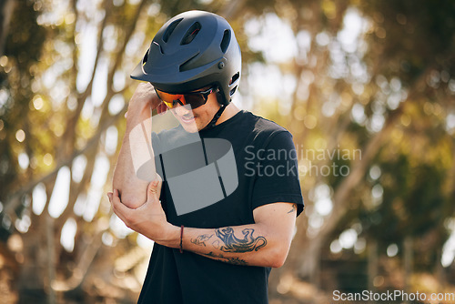 Image of Cycling, arm injury and a sports man in the forest for fitness, training or adrenaline with pain from an accident. Exercise, emergency and a young athlete or rider in the woods for a race or workout