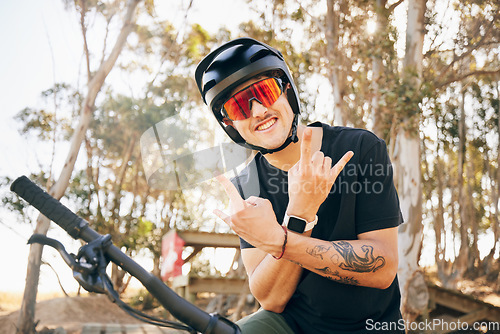 Image of Rock sign, bike and man with helmet in forest on off road cycling workout with happiness and glasses. Portrait, person and smile with hand gestures on bicycle for exercise, challenge and competition