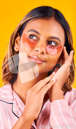 Image of Eye mask, beauty and woman in a studio with skincare, dermatology and cosmetic product. Glow, smile and young female model from Mexico with facial patch for self care treatment by yellow background.