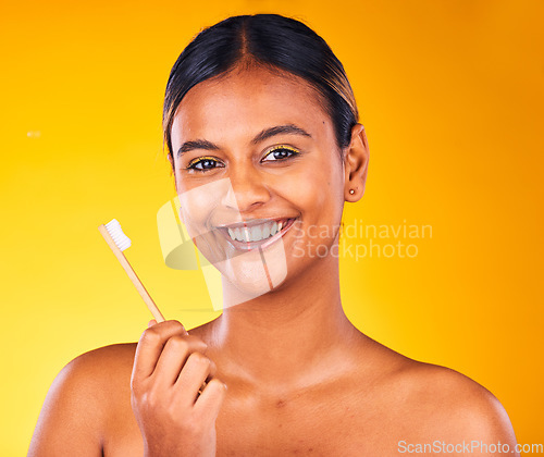 Image of Woman, toothbrush in portrait with smile and dental in studio, health and wellness on yellow background. Bamboo brush, eco friendly orthodontics and teeth whitening for oral care and fresh breath