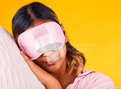 Image of Peace, eye mask and woman sleeping in a studio with pillow for comfortable rest in pajamas. Calm, self care and young female model taking a nap, dreaming and relaxing isolated by yellow background.