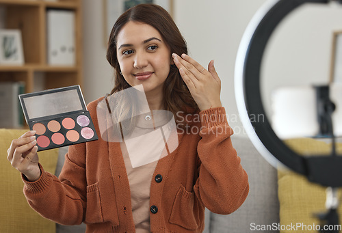 Image of Streaming, makeup and review with a woman influencer in her home to broadcast live content to viewers. Social media, product or tutorial with a young brand ambassador in the living room for cosmetics