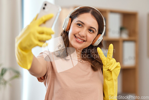 Image of Cleaner woman, selfie and peace sign with smile, headphones and audio streaming for music in home. Happy maid girl, emoji or icon with photography, memory and profile picture on social network app