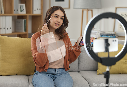 Image of Social media, makeup and tutorial with a woman influencer in her home to broadcast live content to viewers. Streaming, product or review with a young brand ambassador in the living room for cosmetics