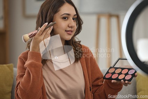 Image of Streaming, makeup and tutorial with a woman influencer in her home to broadcast live content to viewers. Social media, product or review with a young brand ambassador in the living room for cosmetics
