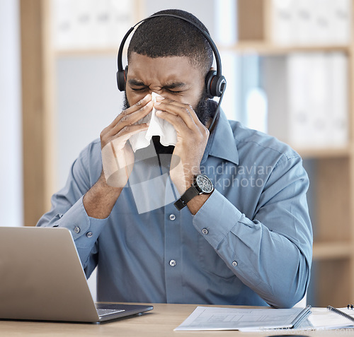 Image of Black man, sick and call center blowing nose with tissue, allergy or flu in customer service at office. African male person, consultant or agent with cold, symptoms or immune virus at workplace