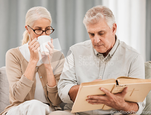 Image of Worship, bible and senior couple with a book in a living room relax, reading and bond with coffee at home. God, faith and retired elderly people with scripture, study or gospel, love and Jesus praise