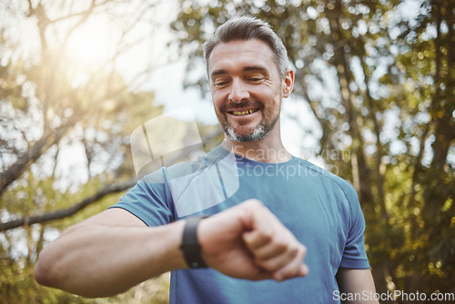 Image of Happy runner man, smart watch and park for check, smile or reading for time, results or fitness in nature. Person, iot clock and monitor for speed, heart rate or smile for exercise, workout or health