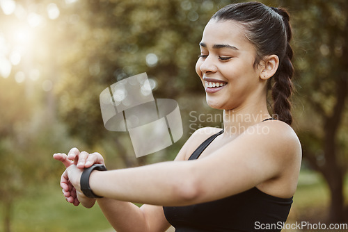 Image of Happy runner woman, smart watch and park for check, smile or reading for time, results or fitness in nature. Girl, iot clock and monitor for speed, heart rate or smile for exercise, workout or health