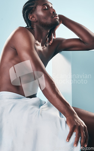 Image of Art, body and relax black man with style, creative graphic and thinking with fitness and workout in studio. Blue background, male model and muscle with skin glow, power and strong chest with beauty
