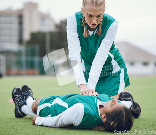 Image of First aid, cpr and emergency with a hockey player on a field to save a player on her team after an accident. Fitness, training and heart attack with a woman helping her friend on a field of grass