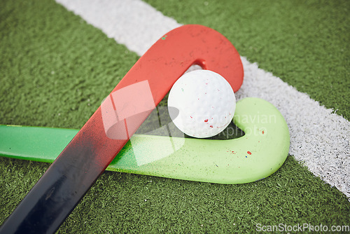 Image of Hockey, stick and ball on green, field or pitch with sports equipment for game, competition or match on ground or floor. Artificial grass, heart or gear on turf for training in sport championship