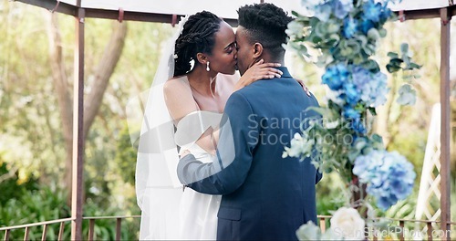 Image of Black couple, wedding and kiss for love, marriage or commitment in embrace or hug together. Married African woman and man kissing affection, trust or relationship of bride or groom in outdoor romance
