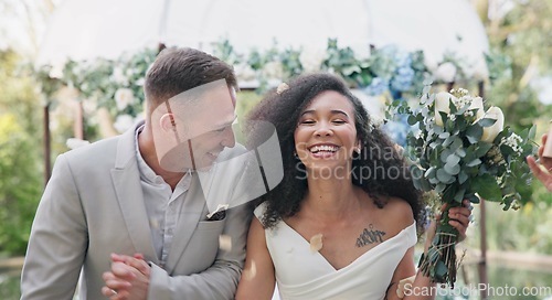 Image of Couple, wedding and celebration with flower confetti for event, walk and outdoor in nature. Girl, happy interracial marriage and floral bouquet in park, holding hands or applause from crowd in aisle