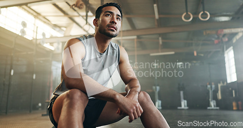 Image of Fitness, breathing and sweating with a tired man in the gym, resting after an intense workout. Exercise, health and fatigue with a young athlete in recovery from training for sports or wellness