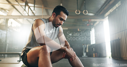 Image of Fitness, breathing and sweating with a tired man in the gym, resting after an intense workout. Exercise, health and fatigue with a young athlete in recovery from training for sports or wellness