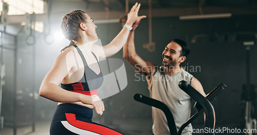 Image of Woman, cycling and personal trainer in high five, motivation or fitness workout, exercise and training at gym. Man coaching female person on bicycle, machine or equipment in cardio at health club