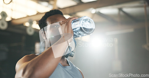 Image of Black man at gym, water bottle and relax to hydrate in muscle development, strong body and fitness. Commitment, motivation and bodybuilder with drink in workout challenge for health and wellness.